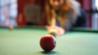 Bilardo ya da gece kulübünde bir kadın bilardo oynuyor. Arka plandaki arkadaş grubu görülebilir. Kavram: bilardo, bilardo, bilardo, bilardo, kulüp, bar, eğlence, kadınlar günü 