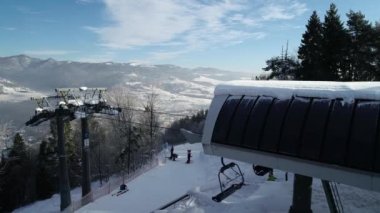 Dağlardaki güzel kayak merkezinin havadan görünüşü. Taze beyaz karla kaplı kış arazisi. Kayak ve snowboard yapmak için mükemmel bir yer. Asansör koltuğu tepeye doğru gidiyor.. 