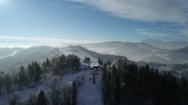 Dağlardaki güzel kayak merkezinin havadan görünüşü. Taze beyaz karla kaplı kış arazisi. Kayak ve snowboard yapmak için mükemmel bir yer. Asansör koltuğu tepeye doğru gidiyor.. 