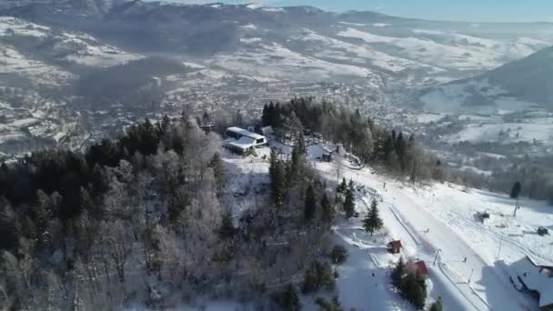 山の中で美しいスキーリゾートの空中ビュー 新鮮な白い雪で覆われた冬の土地 スキーやスノーボードに最適な場所です リフトチェアが丘に登っています — ストック動画