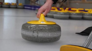 Körling oyunu. Curler kayanın yolundaki buz yüzeyini süpürüyor. Kıvrımlı granit taş kayıyor ve süpürge veya fırça süpürüyor. Konsept: kış oyunları, kış olimpiyatları.