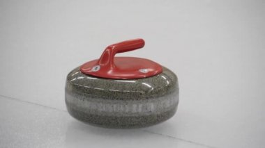 Körling oyunu. Curler kayanın yolundaki buz yüzeyini süpürüyor. Kıvrımlı granit taş kayıyor ve süpürge veya fırça süpürüyor. Konsept: kış oyunları, kış olimpiyatları.