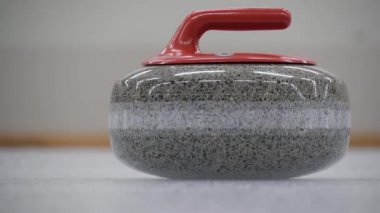 Buz tabakasında kayan kıvrımlı taş. Konsept: Kış takım sporu, olimpiyat oyunları, kıvırma, kıvırma oyuncuları.