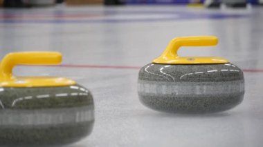 Buz tabakasında kayan kıvrımlı taş. Konsept: Kış takım sporu, olimpiyat oyunları, kıvırma, kıvırma oyuncuları.