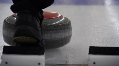 Curling taşı başka bir taşa çarpıyor ve buz tabakasında kayıyor. Konsept: Kış takım sporu, olimpiyat oyunları, kıvırma, kıvırma oyuncuları.
