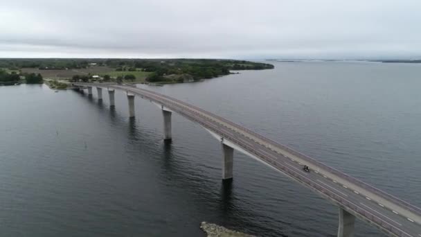 Vue aérienne du paysage scandinave et du pont. Groupe de motocyclistes traversant le long pont moderne. Suède, région d'Oland. Météo typique suédoise .