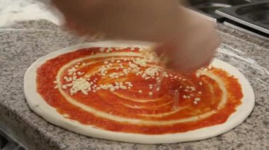 Pizza yapıyorum. Profesyonel bir mutfakta deneyimli bir şef İtalyan pizzası hazırlar. Şef hamuru domates sosu, mozarella ve malzemelerle dolduruyor.