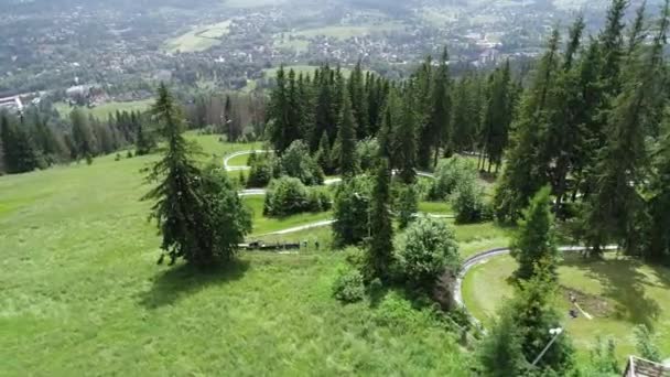 Luftaufnahme der Rodelbahn auf einem grünen Hügel. Abfahrt mit Sommerrodeln. Sommerrodelbahn oder Rodelbahn
