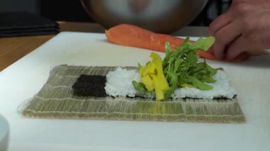 Sushi master preparing fresh and tasty sushi rolls in Japanese restaurant. Concept: Rolling a sushi roll on bamboo mat.Sushi making process, cutting ingredients