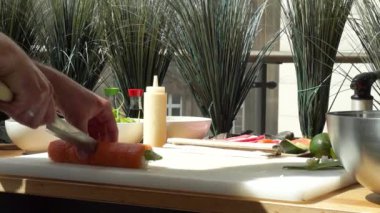 Suşi ustası Japon restoranında taze ve lezzetli suşi ruloları hazırlıyor ve tabağa koyuyor. Konsept: bambu matında suşi rulosu yapmak. Suşi yapmak, malzemeleri kesmek.