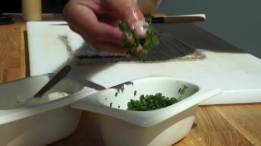 Suşi ustası Japon restoranında taze ve lezzetli suşi ruloları hazırlıyor ve tabağa koyuyor. Konsept: bambu matında suşi rulosu yapmak. Suşi yapmak, malzemeleri kesmek.