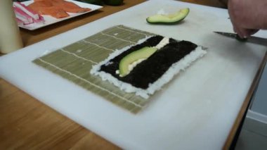 Sushi master preparing fresh and tasty sushi rolls in Japanese restaurant. Concept: Rolling a sushi roll on bamboo mat.Sushi making process, cutting ingredients