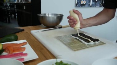 Sushi master preparing fresh and tasty sushi rolls in Japanese restaurant. Concept: Rolling a sushi roll on bamboo mat.Sushi making process, cutting ingredients