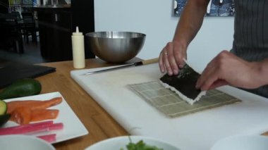 Sushi master preparing fresh and tasty sushi rolls in Japanese restaurant. Concept: Rolling a sushi roll on bamboo mat.Sushi making process, cutting ingredients