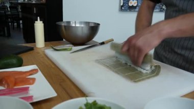 Sushi master preparing fresh and tasty sushi rolls in Japanese restaurant. Concept: Rolling a sushi roll on bamboo mat.Sushi making process, cutting ingredients