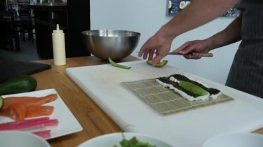 Sushi master preparing fresh and tasty sushi rolls in Japanese restaurant. Concept: Rolling a sushi roll on bamboo mat.Sushi making process, cutting ingredients