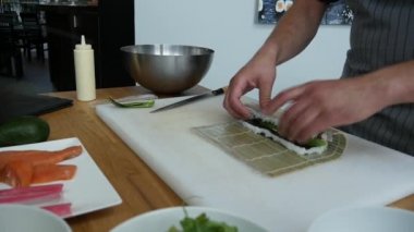 Sushi master preparing fresh and tasty sushi rolls in Japanese restaurant. Concept: Rolling a sushi roll on bamboo mat.Sushi making process, cutting ingredients