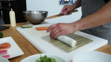 Sushi master preparing fresh and tasty sushi rolls in Japanese restaurant. Concept: Rolling a sushi roll on bamboo mat.Sushi making process, cutting ingredients