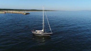 Deniz manzaralı bir tatil köyü ve güzel bir yelkenli ya da gün doğumundan sonra sakin denize açılacak bir yat. Polonya 'da Baltık Denizi, yaz mevsimi. Denizin ortasında yalnız bir denizci.