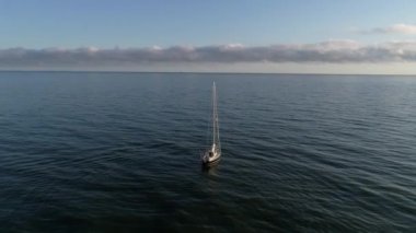 Güneşin doğuşundan sonra sakin denize açılan güzel yelkenli ya da yatın hava manzarası. Polonya 'da Baltık Denizi, yaz mevsimi. Denizin ortasında yalnız bir denizci.