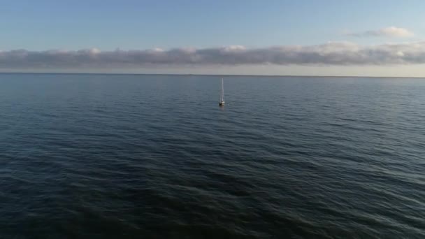 Güneşin doğuşundan sonra sakin denize açılan güzel yelkenli ya da yatın hava manzarası. Polonya 'da Baltık Denizi, yaz mevsimi. Denizin ortasında yalnız bir denizci.