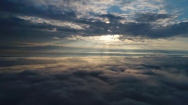 Güneş doğarken bulutların üzerinde uçan hava manzarası. Hareket eden kabarık bulutların manzarası. İHA yüksekten uçuyor. Logo veya metin için mükemmel bir arkaplan. Bulutların ve stratosferin üstündeki düzlem perspektifi