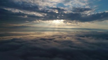 Güneş doğarken bulutların üzerinde uçan hava manzarası. Hareket eden kabarık bulutların manzarası. İHA yüksekten uçuyor. Logo veya metin için mükemmel bir arkaplan. Bulutların ve stratosferin üstündeki düzlem perspektifi