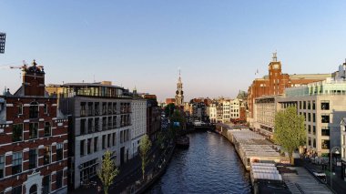 İlkbaharda ya da yazın günbatımında Amsterdam 'daki ünlü yerlerin hava manzarası. Kanal ve eski merkez bölgenin üzerinde uçuyor. Arka planda Munttoren Çan Kulesi var. Güzel sıcak renkler