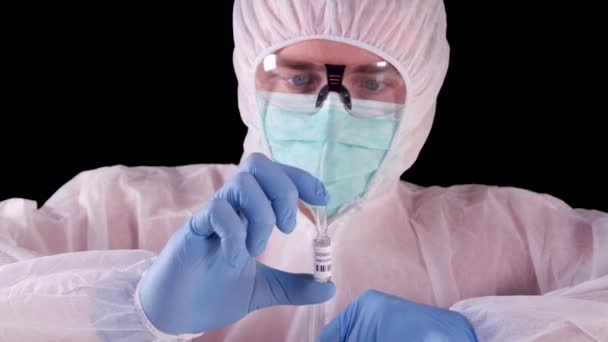 Mężczyzna Białym Mundurze Ochronnym Masce Okularach Pokazujący Szczepionkę Strzykawkę Celu — Wideo stockowe