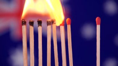 Evde kal, Coronavirüs salgınını önle. Avustralya haritasının arka planında kibrit yakma. Kavram: Yayılan salgın, domino etkisi, COVID-19, Wuhan virüsü, izole edilmiş kibritler, Dünya için dua et.
