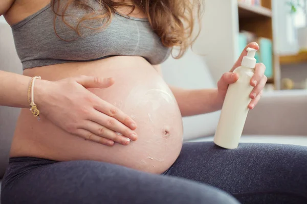 Pregnant woman applying  cream on a belly. Pregnancy cream on a woman belly  pregnant.