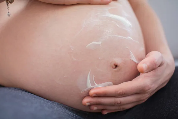 Pregnant woman applying  cream on a belly. Pregnancy cream on a woman belly  pregnant.