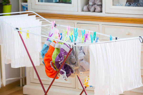 Diapers laundry indoors . Eco nappy wash drying in a room . Colorful diapers drying. Reusable nappy and soaker. 