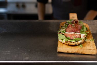 Şef restoranda çiğ jambonlu pizza servis ediyor. Tahtada servis ediliyor.