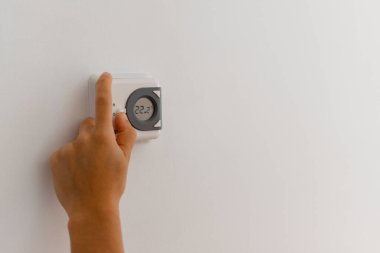 Evde dijital oda termostatı kullanan tanınmayan bir kişi.