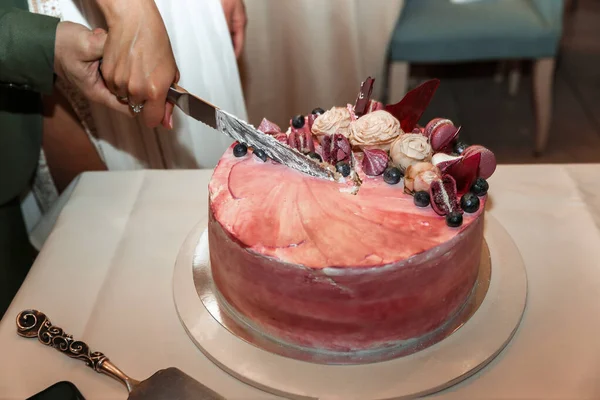 用粉红饼干和蓝莓装饰的湿蛋糕 新娘和新郎用刀切蛋糕 — 图库照片