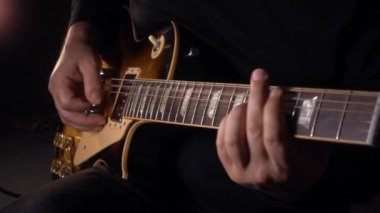 Gitarist stüdyoda gitar çalıyor. Yavaş çekim 50 peni. koyu arkaplan