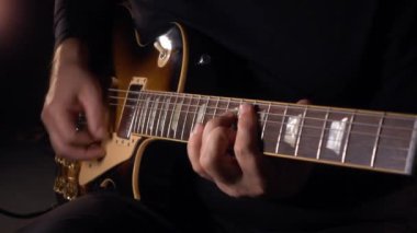 Gitarist stüdyoda gitar çalıyor. Yavaş çekim 100 peni. koyu arkaplan