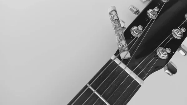 ギターのヘッドストックを閉じて銀行券をコピースペースで巻き上げた 黒と白 — ストック写真