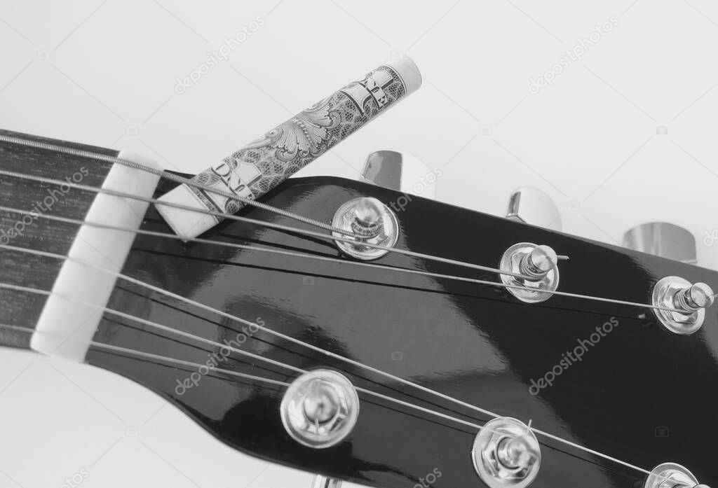 guitar headstock closeup and banknote rolled up  with copy space . black and white