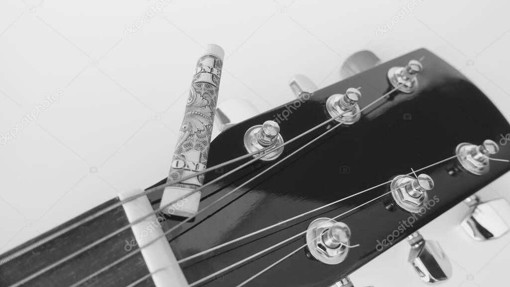 guitar headstock closeup and banknote rolled up  with copy space . black and white