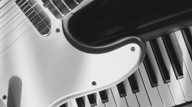 Elektro gitar ve piyano klavyeleri güneş ışığında yakınlaşıyor. Işık ve gölgeler. siyah ve beyaz