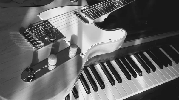 electric guitar and piano keyboards closeup in the sun light . Light and shadows . black and white