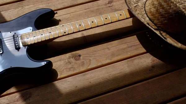 木制木板上的电吉他和牛仔帽特写 — 图库照片