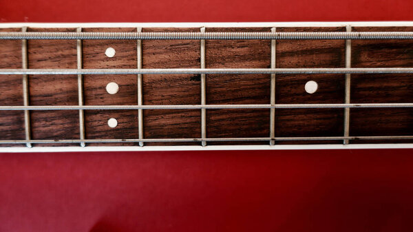 Bass guitar neck closeup . Copy space . Red background