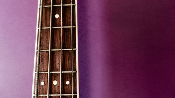 Bass guitar neck closeup . Copy space . Purple background