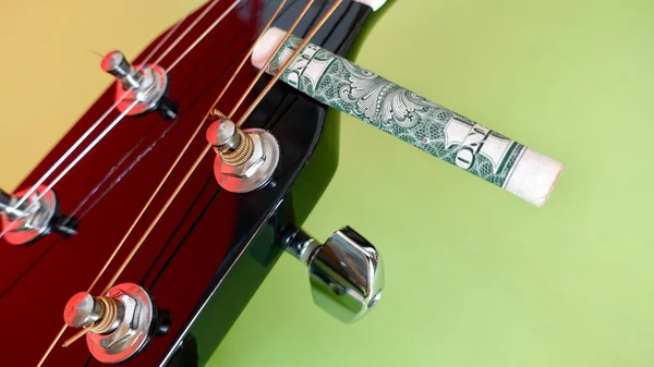 ギターのヘッドストックとドル札がわらにねじ曲げられた コピースペース付きカラー背景 — ストック写真