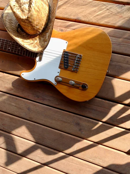 vintage electric guitar and cowboy hat on the wooden boards.