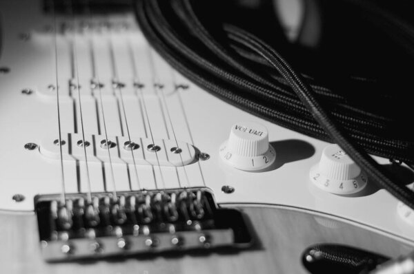 Electric guitar closeup and guitar cable . Dark background
