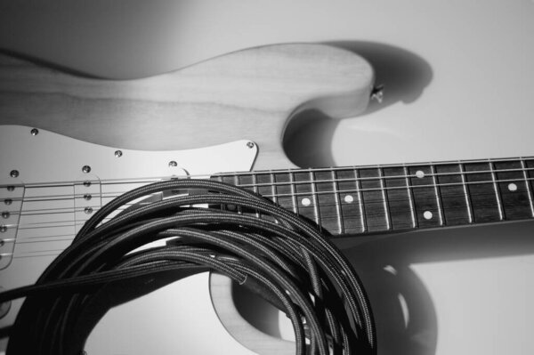 Electric guitar and guitar cable . Black and white